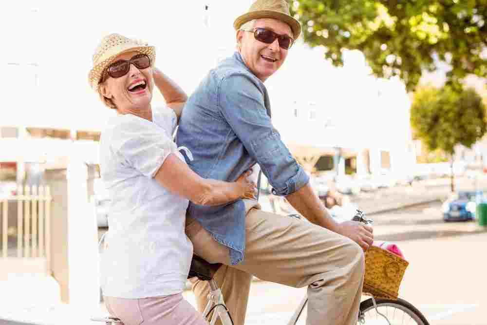An older couple riding a bicycle on a sunny day.