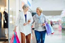 Two women walking down a shopping mall with shopping bags.