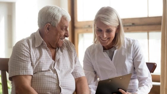 A nurse examines a clipboard alongside an elderly man, ensuring the quality of life for seniors.