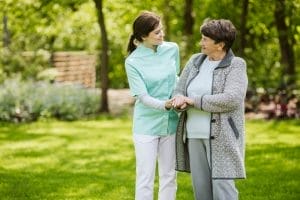 A nurse talking to an elderly woman in a park.