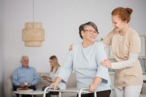 A woman is helping an elderly woman with a walker.