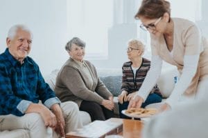A group of elderly people sitting on a couch with a plate of food.