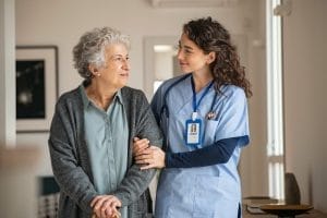 A nurse is talking to an elderly woman in a hallway.