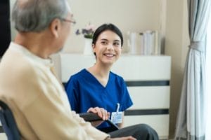 A nurse sitting in a wheelchair with an elderly woman.