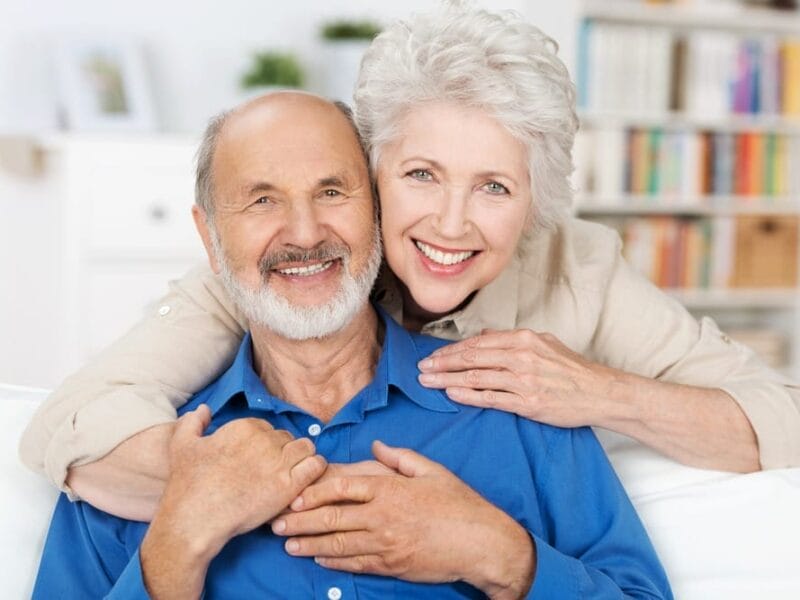 An older couple embracing on the couch after being discharged from the hospital.